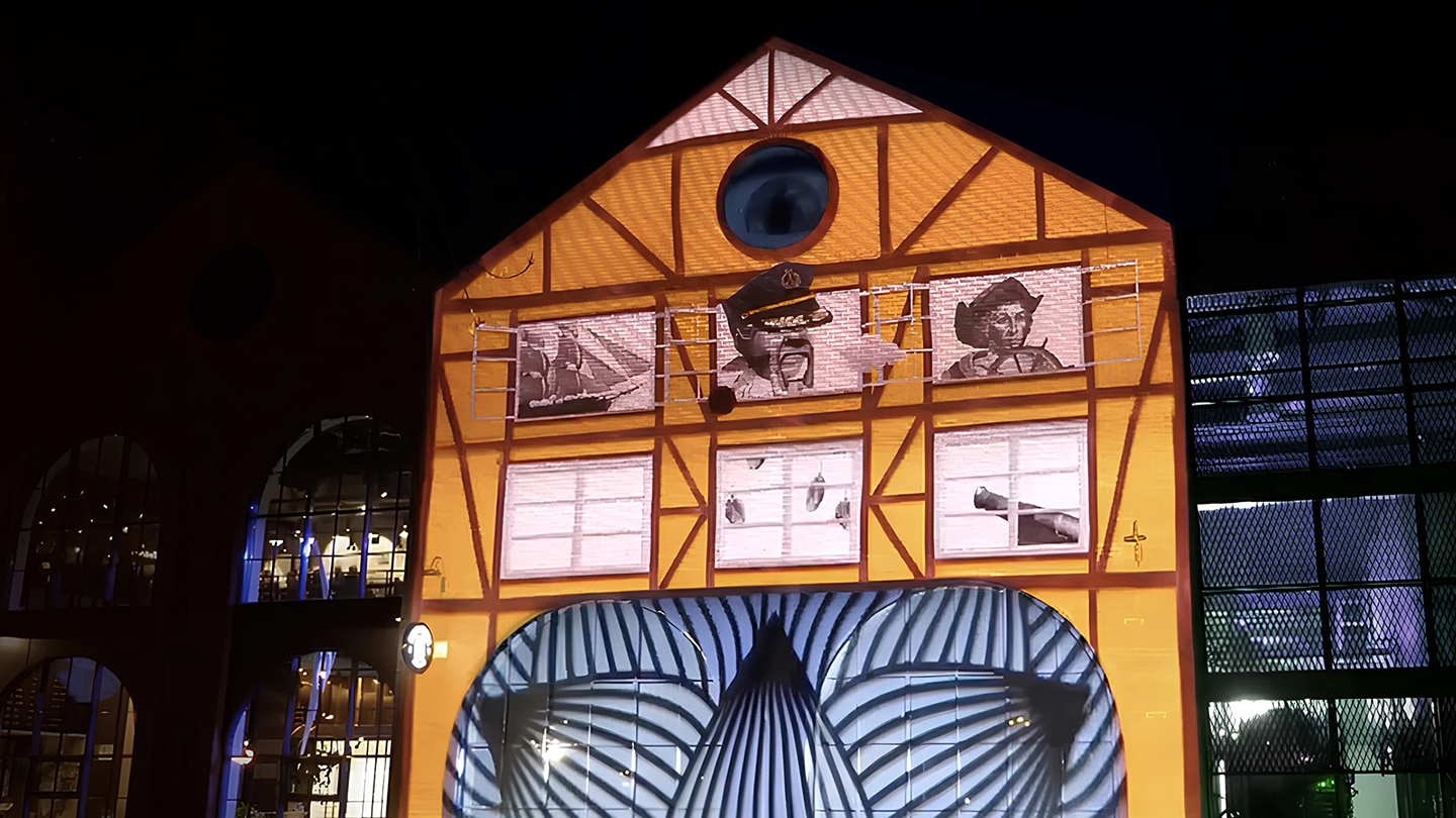 Triangular rooftop with blinking eye projected into the brewery’s gable — combining symbolism and humor.