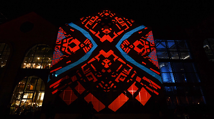Klaipeda 700 light projection showing a geometric red-and-blue kaleidoscopic pattern across a city building facade.